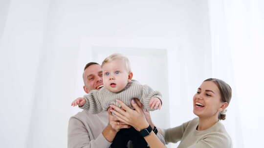 一对微笑的白人夫妇从两边抱着一个小婴儿。