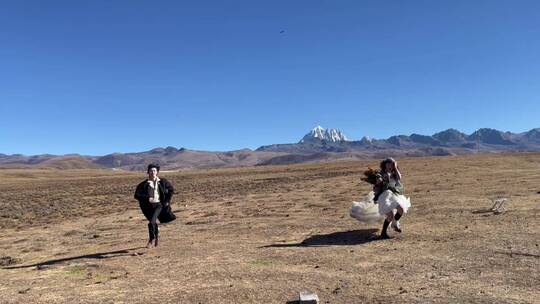 高原枯黄草原雪山情侣奔跑拍写真婚纱视频素材模板下载