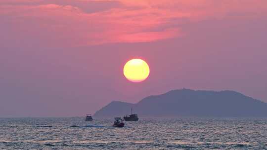 海南三亚橘红色夕阳晚霞下行驶的豪华游艇