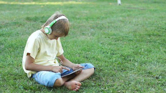 男孩戴着耳机听音乐并使用平板电脑