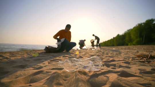日落时分，一群志愿者用塑料袋在沙滩上收集视频素材模板下载