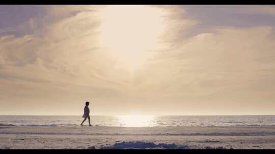 女人走在日出的沙滩边的剪影