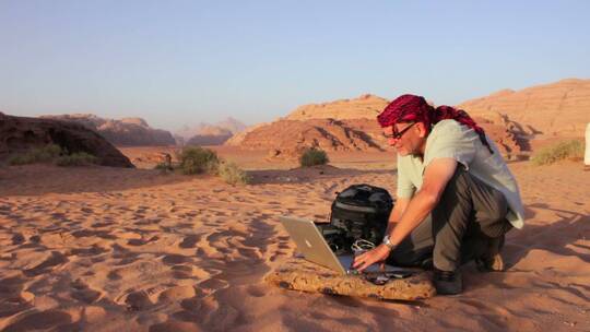 一个男人在沙漠中的笔记本电脑上工作