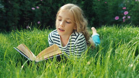 女孩趴在户外草地上阅读
