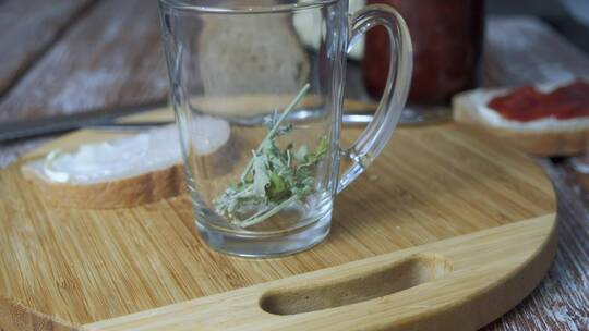 制作花草茶。将水倒入玻璃杯和花草茶