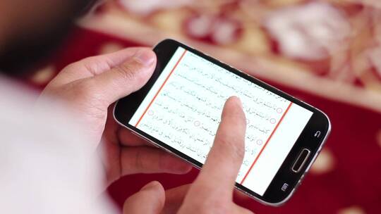 穆斯林男子在手机上阅读古兰经