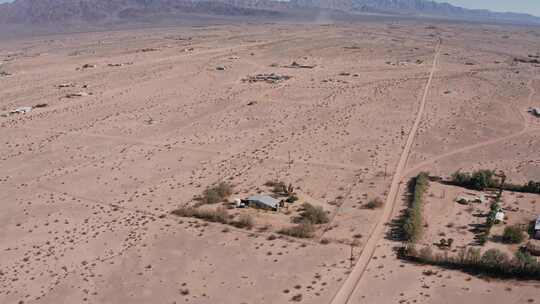 加州空旷的莫哈韦沙漠中一所孤独的房子的下降特写平移航拍。4K