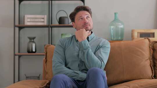 思考中年男子坐在家里的沙发上