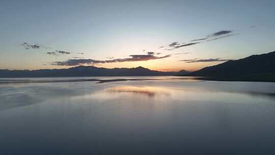 赛里木湖风平浪静的湖面倒映着美丽的朝霞