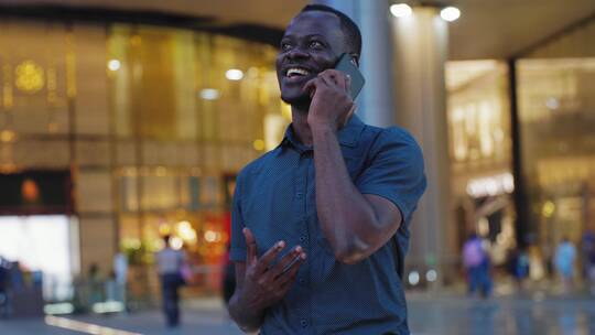 非洲男青年在夜幕下成都街头开心打电话视频素材模板下载