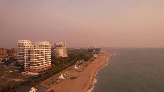 落日余晖海景房风力大风车海边沙滩游客