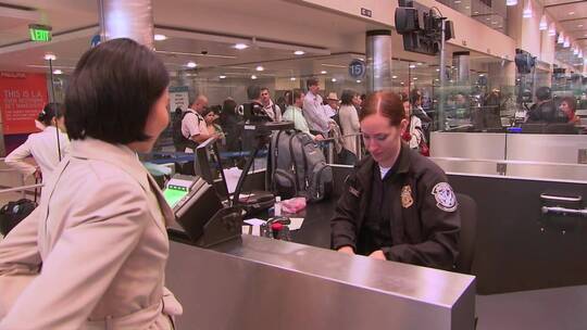 进入国际机场航站楼的乘客通过美国海关并被拍照和指纹