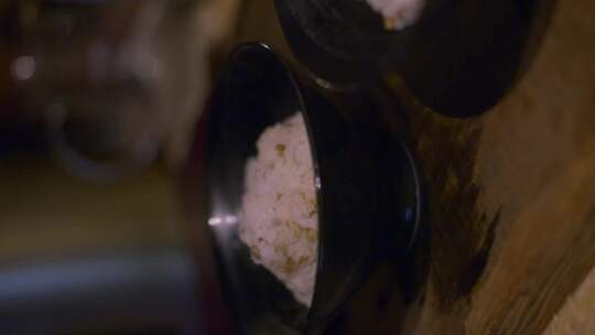 2个装满米饭的黑色碗坐在木制桌面上冷却，