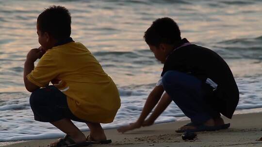 日落时在海滩上的男孩们