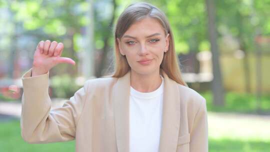 户外拇指朝下的女商人肖像