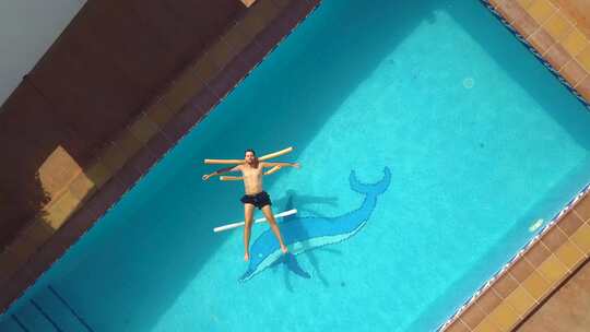 空中升空，一名男子冷冷地漂浮在游泳池上。