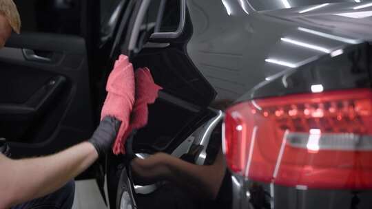 洗车工人用毛巾擦亮车翼的照片。
