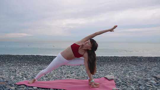 女士在圆石滩的海边做瑜伽运动视频素材模板下载