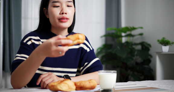 年轻的亚洲女人喜欢在家里的餐桌上吃早餐。