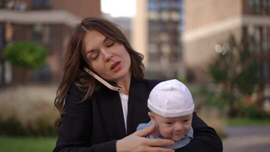 特写女商人抱着一个婴儿，挥手打手机