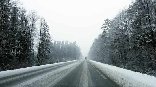 危险和可怕的POV驾驶在一辆卡车后面在雪暴期间在森林道路在白天