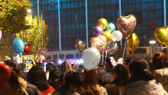 城市节日街头夜晚庆祝跨年拿着气球的人群