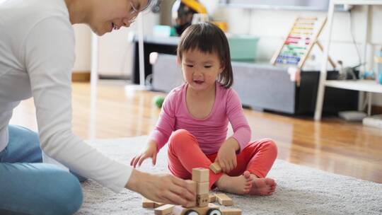 小女孩和妈妈在一起在家里玩耍搭积木