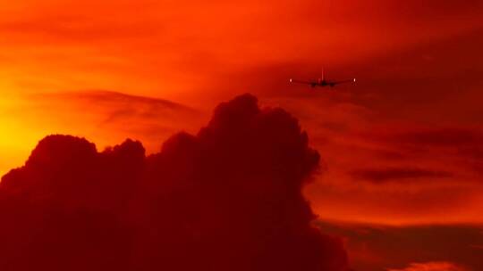 在红色多云的天空中飞行的飞机
