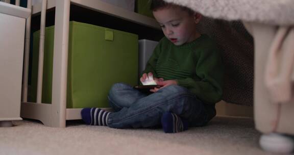 男孩盘腿坐在地毯上玩手机