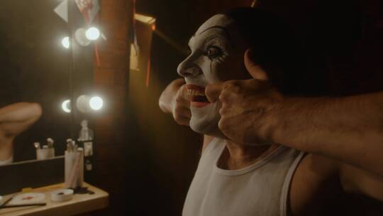 男子在对着镜子练习小丑表情