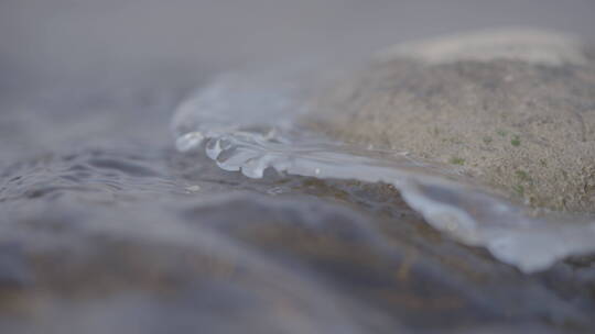 湍急水流拍打冰岸石头特写4k50帧灰片