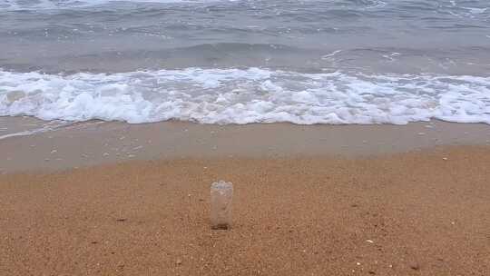 在浪花与微风中，一只瓶子静静躺在沙滩上