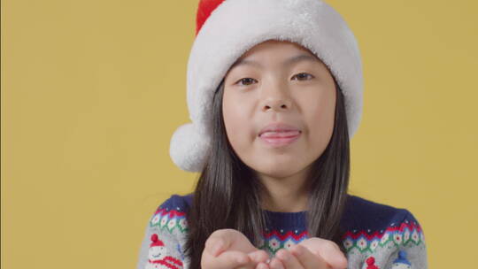 戴圣诞老人帽的孩子在镜头前吹雪视频素材模板下载