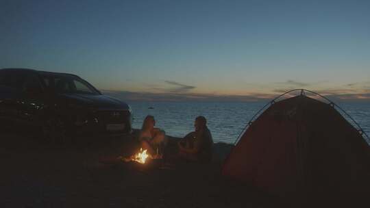 一对情侣夜晚在海边搭帐篷露营