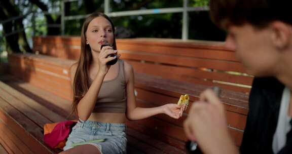 肩上快乐的十几岁女孩在约会期间喝苏打水和