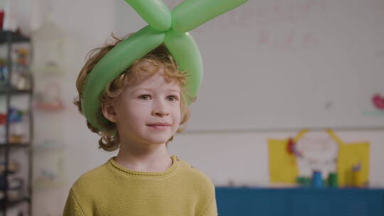 戴着绿色长气球的小男孩肖像特写
