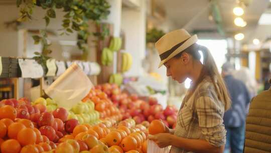 一名妇女在食品店将橙子放入塑料袋