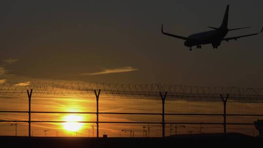 夕阳下飞机降落在机场的剪影