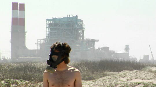 一个戴着防毒面具的人站在发电厂前