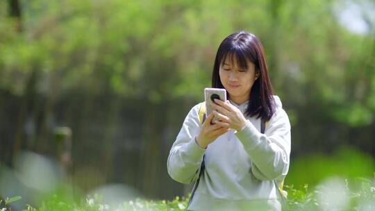 年轻阳光活力女孩春天户外踏青游玩刷手机