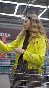 穿黄色夹克的女人在超市购物时阅读产品标签