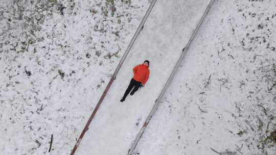 航拍男人躺在鹿儿坪森林中的雪地上