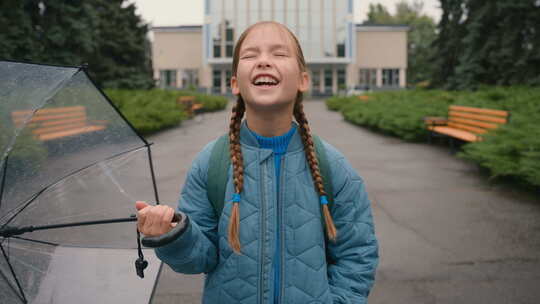 快乐的小女孩撑着雨伞倾盆大雨看着天空湿漉