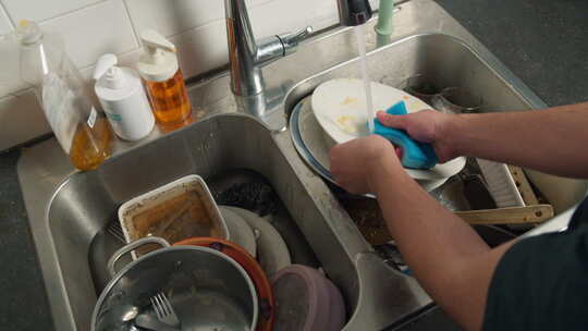男人在厨房的脏水槽里用手洗碗视频素材模板下载
