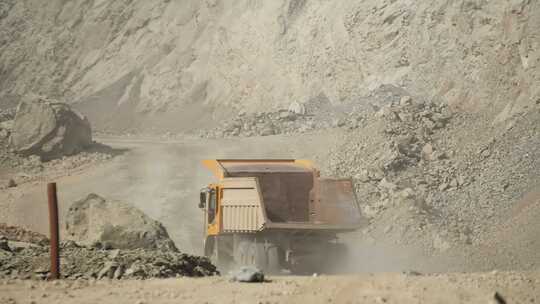 一辆黄色大卡车正在采石场的路上行驶，用于开采山地矿石