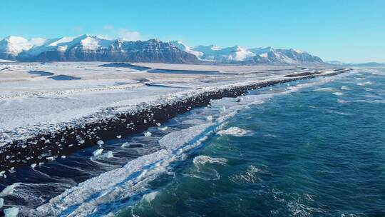 航拍冬季雪后的海岸礁石海浪