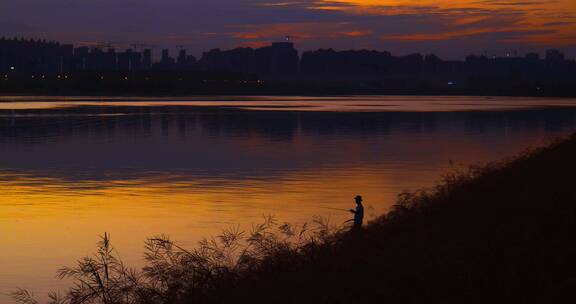 4k夕阳下江边钓鱼的男人