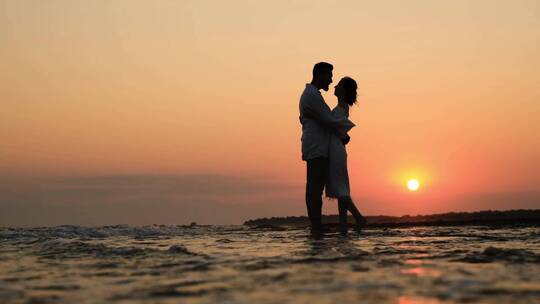 情侣海边夕阳下拥抱表达爱意