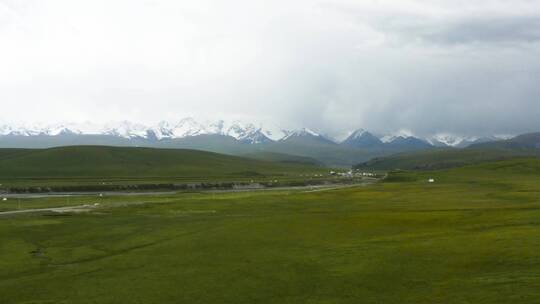 航拍新疆独库公路上的草地雪山