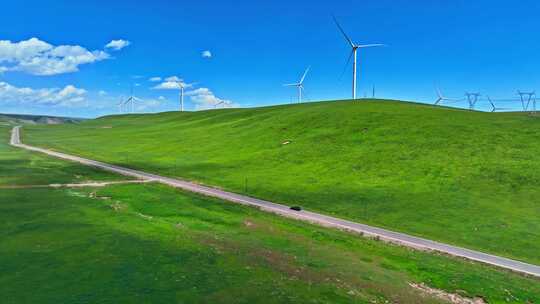 新能源电动车行驶在祁连山草原风力发电场